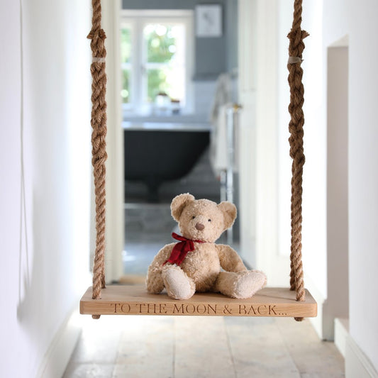 Oak and rope swing with a teddy bear sitting on it.  Shown in a house.